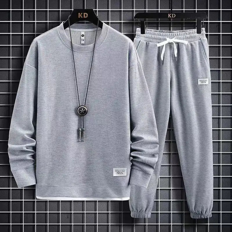 Gray sweatshirt and pants set on hangers against a grid background