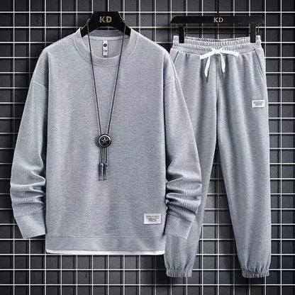 Gray sweatshirt and pants set on hangers against a grid background